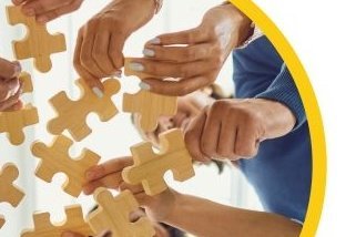 Ansicht von unten nach oben. Viele Hände halten Puzzleteile.